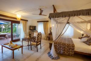 a bedroom with a canopy bed and a living room at The Maji Beach Boutique Hotel in Diani Beach