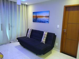 czarna kanapa w salonie ze zdjęciem na ścianie w obiekcie Apartamento Praia do Forte VIP w mieście Cabo Frio