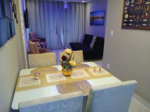 uma mesa de jantar com um vaso de flores em Apartamento Praia do Forte VIP em Cabo Frio