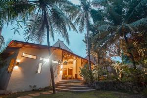 a house with palm trees in front of it at Adara Homestay in Banyuwangi