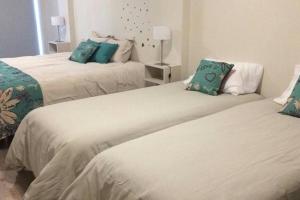 1 dormitorio con 2 camas con sábanas blancas y almohadas azules en Brc Apartment en San Carlos de Bariloche