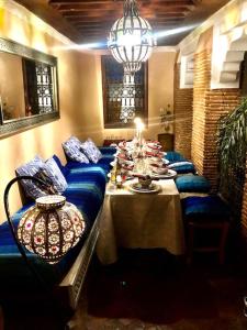 ein Esszimmer mit einem langen Tisch und blauen Sofas in der Unterkunft RIAD DES DEUX MERS in Marrakesch