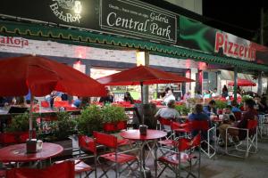 a restaurant with red tables and chairs and people sitting at it at Hotel Central park in Santa Clara del Mar