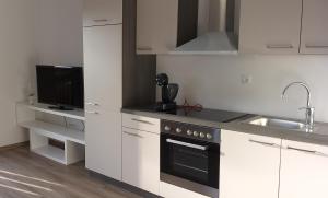 a kitchen with white cabinets and a black oven at Apartmaji Pika in Cerklje na Gorenjskem