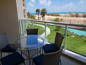 een tafel en stoelen op een balkon met uitzicht op het strand bij Aquiraz Riviera Beach Place Golf Residence in Aquiraz