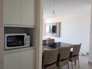 a kitchen with a table with chairs and a microwave at Beach Place Aquiraz Riviera in Aquiraz