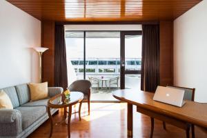 a living room with a couch and a table with a laptop at Amari Don Muang Airport Bangkok in Bangkok