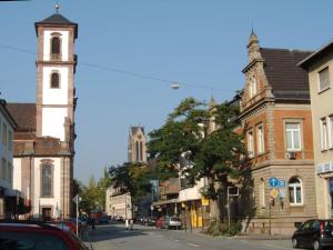 eine Stadtstraße mit einem Uhrturm und Gebäuden in der Unterkunft Be my Guest in Mannheim in Mannheim