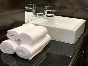 a bathroom with a sink and a pile of towels at Luxury Apartment, 3 min Walk to Beach, Albufeira in Guia +38 photos