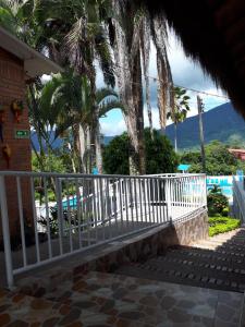 um banco em frente a uma casa com palmeiras em Hotel Villa Amparo em Chinauta