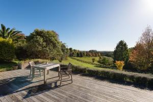 una mesa y 2 sillas sentadas en una terraza de madera en Puketotara Lodge, en Kerikeri