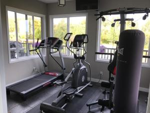 un gimnasio con máquinas de correr, cinta de correr y ventanas en Dragonfly Inn Loft Suite en Sherwood Park