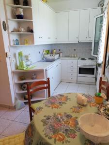 cocina con mesa y cocina con armarios blancos en Maria, en Vathírrevma