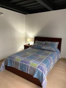 a bedroom with a bed with a blue and green quilt at Apto zona colonial lindísimo 201 in Zipaquirá