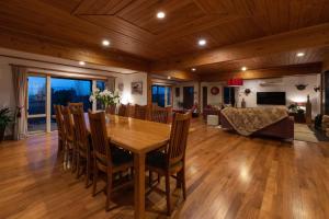 a dining room and living room with a wooden table and chairs at Puketotara Lodge in Kerikeri