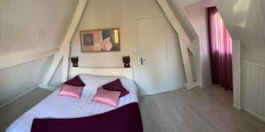 um quarto com uma cama com duas almofadas cor-de-rosa em Gite de la Baie d'Authie em Groffliers
