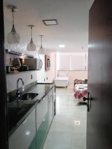 een keuken met een wastafel en een woonkamer bij Sol Victoria Marina Lofts in Salvador