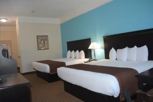 a hotel room with two beds and a desk at Baymont by Wyndham Galveston in Galveston