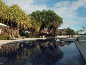 een zwembad met stoelen, parasols en bomen bij Palm Coast Luxury Rentals in Esterillos Este