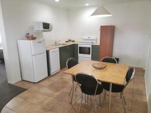 cocina con mesa, sillas y nevera blanca en Bks Egmont Motor Lodge, en New Plymouth