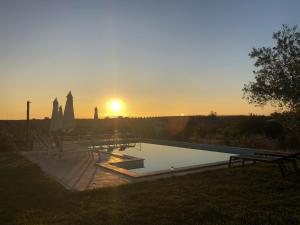 a pool with the sun setting in the background at Monte da Estrela - Country House & SPA in Mourão