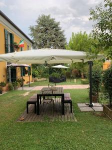 a table and bench under a white umbrella at Medoacvs B&B in Fiesso dʼArtico