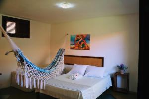 a bedroom with a bed with a hammock at Pouso do Kite Pousada Flecheiras in Flecheiras