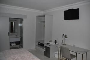 Schlafzimmer mit einem Bett, einem Tisch und einem TV in der Unterkunft Prisatt Boutique Hotel in Onverwacht
