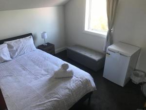 a bedroom with a white bed and a window at Sandy Feet Lodge in Christchurch