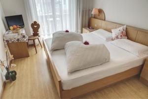 um quarto com 2 camas com lençóis brancos e almofadas em Hotel & Residence Sylvanerhof em Chiusa