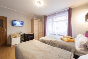 a bedroom with two beds and a tv on the wall at PIONOW Pokoje WaWa - adults only in Krynica Morska