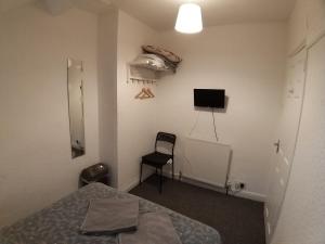 a room with a bed and a chair and a television at Belfast Town House in Belfast