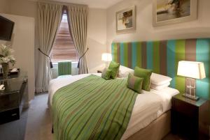 ロンドンにあるニュー リンデン ホテルのベッドルーム1室(緑と白の毛布付きのベッド1台付)