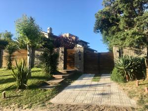 a garden with a fence and a wooden walkway at Tierra Mora Casas de alquiler, ESTA PROPIEDAD SE GESTIONA SOLO POR ESTA PAGINA, SOLO GRUPOS FAMILIARES in Villa Gesell