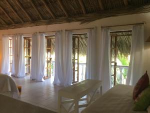 Una habitación con cortinas blancas y una cama y una mesa. en Hacienda La Rusa, en Barra de Potosí