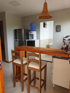 cocina con encimera de madera y 2 taburetes en Rota da Praia II, en Barra Grande