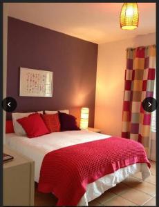 um quarto com uma cama grande e almofadas vermelhas em Casa de férias na Praia Verde Casa de Charme em Castro Marim