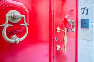 eine rote Tür mit einem goldenen Schlüssel drauf. in der Unterkunft Entire House of Character - Castelinho Sao Marcos in Senglea