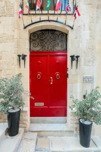 a red door on a building with two plants at Entire House of Character - Castelinho Sao Marcos in Senglea