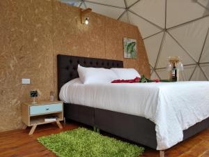 a bedroom with a bed with white sheets and red flowers at Glamping Aquamonti in Supatá