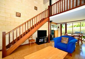 a living room with a blue chair and a staircase at Cowrie Chalet in Augusta