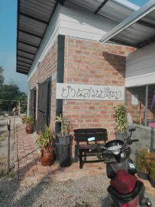 una motocicleta estacionada frente a un edificio de ladrillo en บ้านสวนปวิชญา เกษตรอินทรี, en Fang