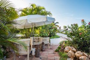 a patio with a bench and an umbrella at Sint Maarten Blue Dream 1BR (C) in Cupecoy