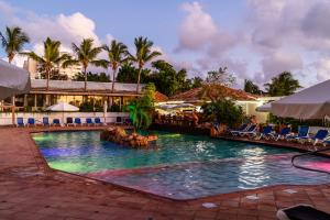 una piscina en un complejo con palmeras y sillas en Sint Maarten Blue Dream 1BR (C), en Cupecoy