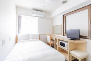 a hotel room with a bed and a desk and a tv at HOTEL MYSTAYS Higashi Ikebukuro in Tokyo
