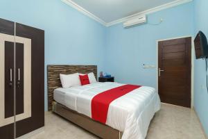 sypialnia z łóżkiem z czerwonym i białym kocem w obiekcie RedDoorz Syariah @ Mora Garden Bungo w mieście Bebeko