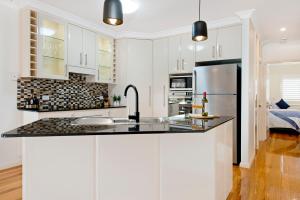 a kitchen with white cabinets and a black counter top at Adrift at Dolphin Cove Apt 5 - riverfront modern in North Haven