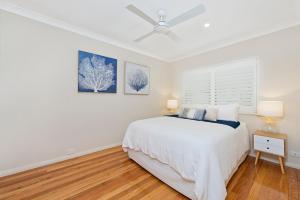 a white bedroom with a bed and a ceiling fan at Adrift at Dolphin Cove Apt 5 - riverfront modern in North Haven