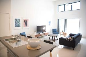 Acacia Villa في نوسا هيدز: غرفة معيشة مع مطبخ وغرفة معيشة مع طاولة