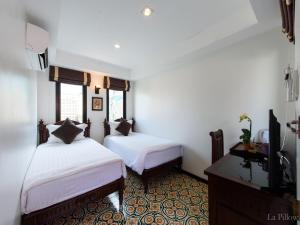 a bedroom with two beds and a tv in it at La Pillow 8 in Chiang Mai